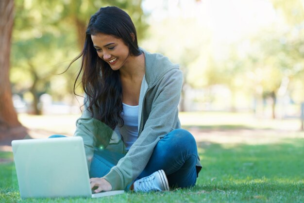Posso estar conectado em qualquer lugar Uma jovem trabalhando em seu laptop em um parque