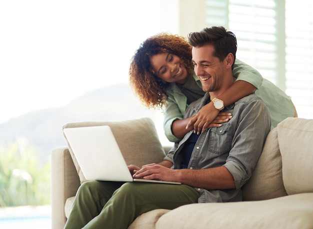 Foto posso ver a foto recortada de um jovem casal afetuoso usando um laptop em sua casa