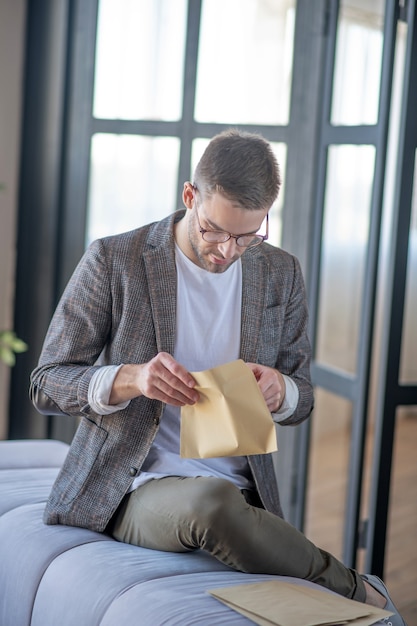 Post abrufen. Ein konzentrierter Mann öffnet einen Papierumschlag