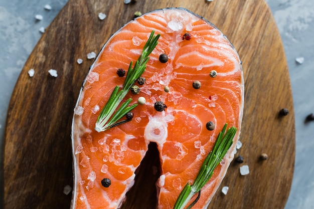 Posta de peixe salmão cru fresco com especiarias na placa de madeira