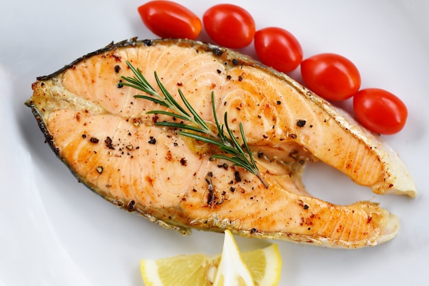 Posta de salmão com ervas e especiarias alecrim limão tomate em um prato close-up cozido salmão filé de peixe filé de frutos do mar