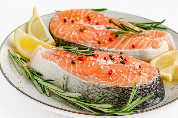 Posta de salmão crua com pimenta, sal marinho, alecrim e limão em branco. Vista superior, dieta ceto e conceito de alimentação saudável.