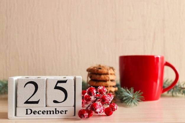 Postal de Natal com biscoitos no galho da árvore de cupfir de madeira, calendário datado de 25 de dezembro