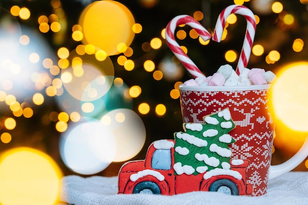 Postal de Natal com caneca vermelha de biscoito de gengibre com enfeite de natal na luz bokeh do natal