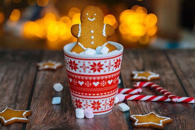 Postal navideña con hombre de jengibre taza roja con adorno navideño