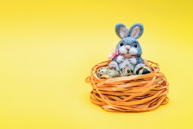 Postal de Pascua. En blanco para una postal con un lugar para insertar texto. Conejito de Pascua y huevos de codorniz sobre fondo amarillo