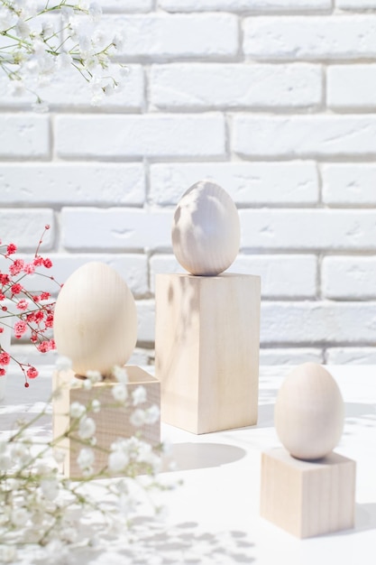 Postal de pascua con tres huevos de madera en podios y espacio de copia de flores