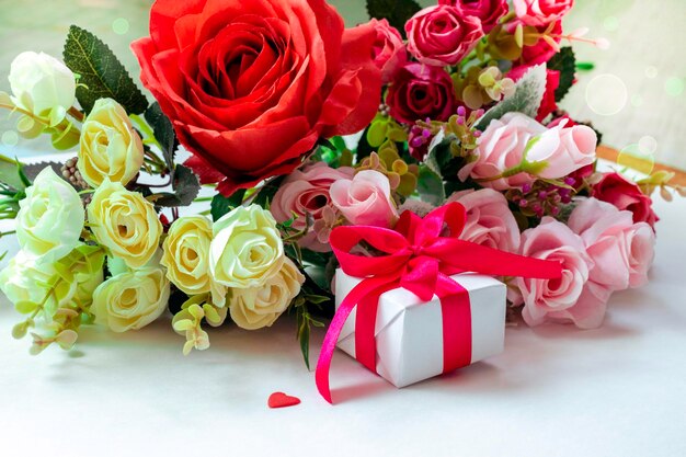 Una postal para las rosas del día de San Valentín y un regalo con cinta roja en un fondo blanco