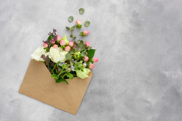 Postal con sobre de papel kraft abierto lleno de flores de primavera