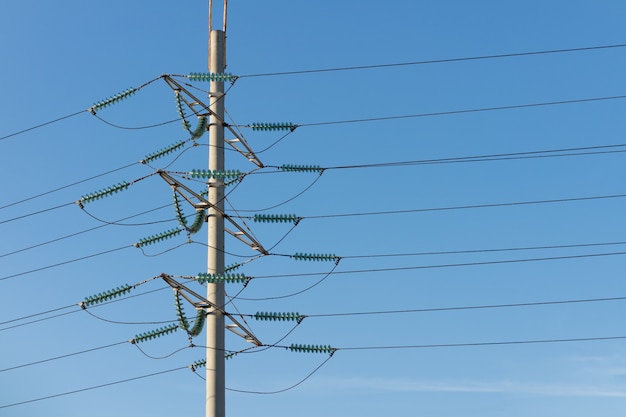 Foto poste de alta tensión contra el cielo azul.