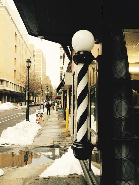 El poste de la barbería en la pared por la calle durante el invierno