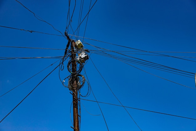 Poste de calle con muchos cables eléctricos y cables de fibra óptica, cable de fibra óptica contra el cielo azul.