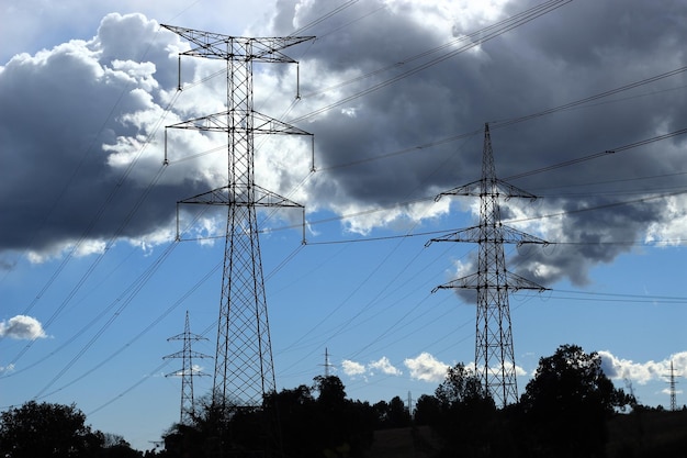 Poste de alta tensão ou torre de energia com nuvens ao fundo.