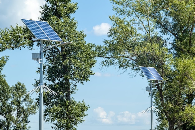 Poste de luz com sistema de painel solar na estrada com céu azul e árvores Iluminação pública autônoma usando painéis solares Lâmpada de rua com baterias do sol Sistemas alternativos de energia renovável