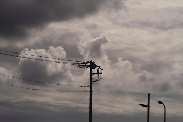 El poste de electricidad contra el cielo nublado