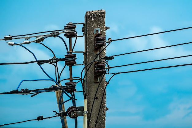 Poste eléctrico con aisladores y alambres en el cielo azul