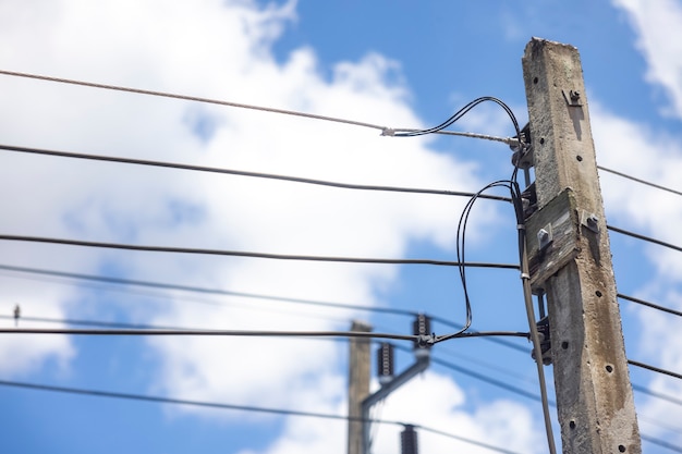 Poste eléctrico y línea eléctrica en un día claro con cielo azul y nubes blancas de fondo.