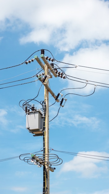 Poste eléctrico y transformador en un cielo azul.