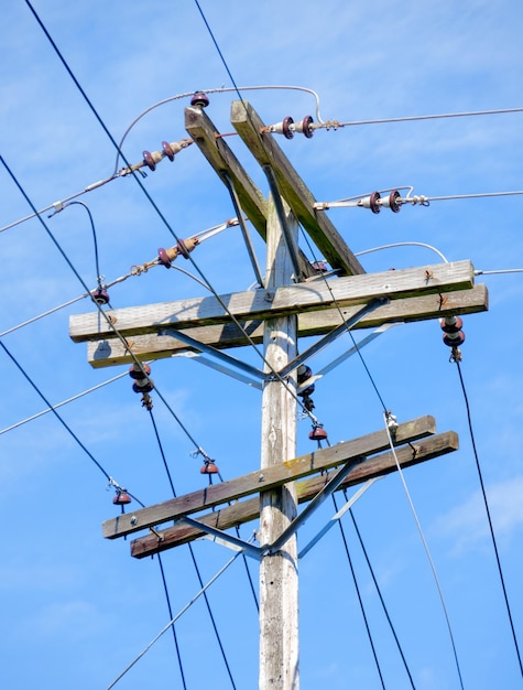 Poste elétrico e poste de eletricidade de madeira de fios no fundo do céu azul