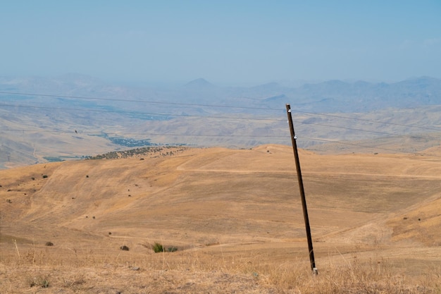 Poste de energía con pintoresco paisaje otoñal armenio en el fondo Campos y prados en las montañas de la región de Armenia Fotografía de archivo