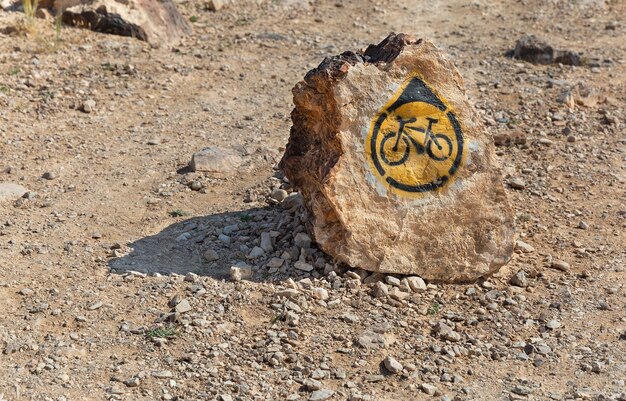 Poste indicador de la ruta de la bicicleta en una piedra en el desierto de Israel