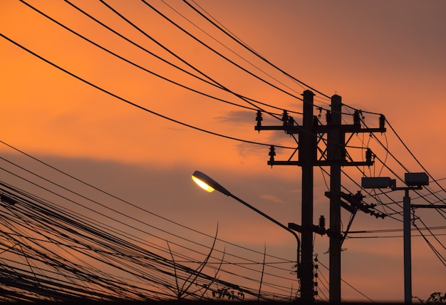 Poste de la lámpara y línea telefónica con un fondo puesta de sol en la calle