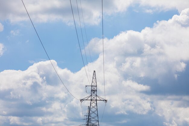 Foto un poste de línea de alta tensión contra un cielo con nubes blancas