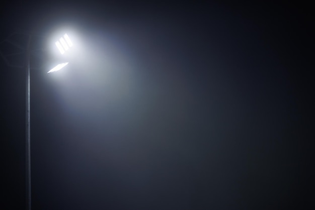 Poste de luz con dos lámparas led en la noche de niebla