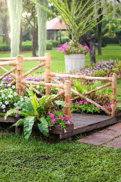 Foto poste de madera, camino y jardín de flores.