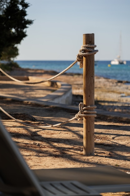 Poste de madera con cuerdas en la playa con vistas al mar y un yate en un ambiente tranquilo en el resort nocturno