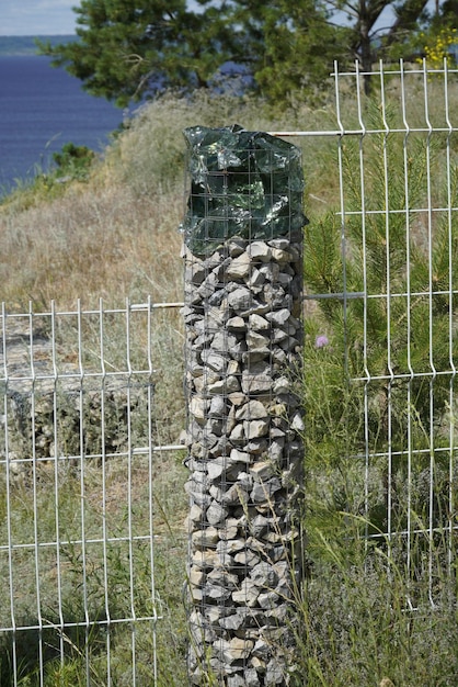 Poste de valla hecho de malla metálica con piedras en el interior