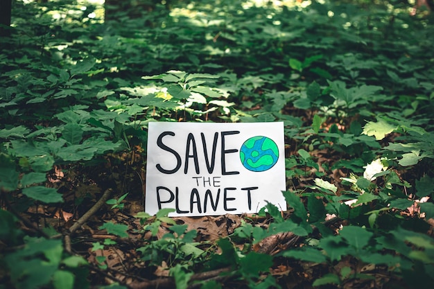 Poster mit der Aufschrift Save the Planet im Wald zwischen den Pflanzen