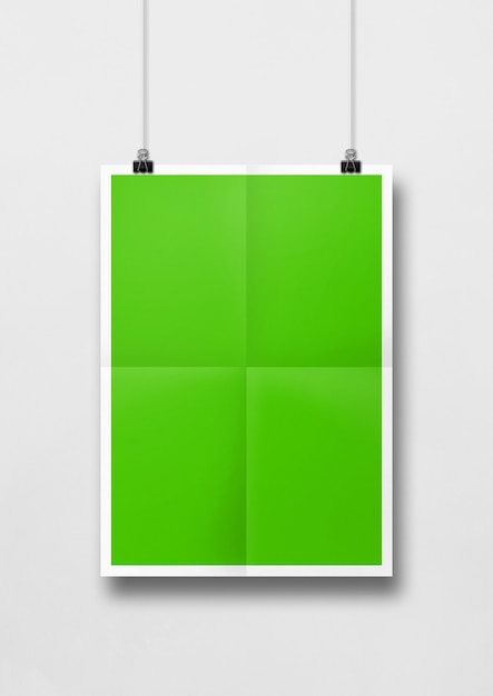 Póster verde doblado colgado en una pared blanca con clips. Plantilla de maqueta en blanco