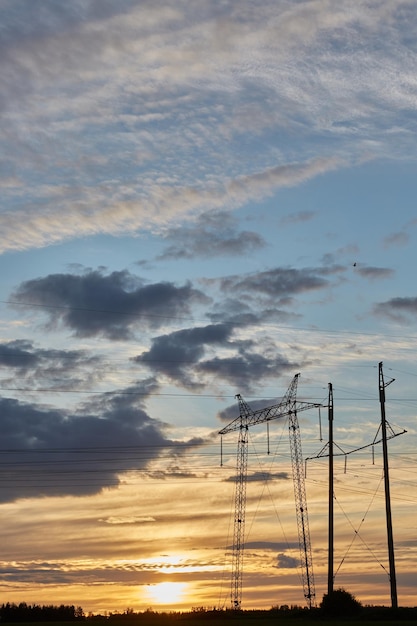 Postes de eletricidade com fios ao pôr do sol.