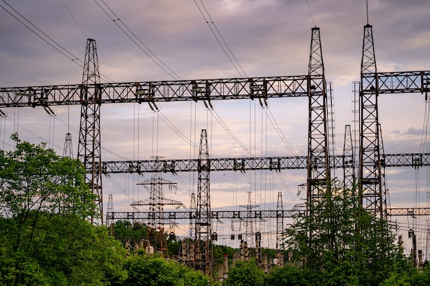 Postes de eletricidade sustentando o fornecimento de energia em uma paisagem rural durante o pôr do sol. Foco seletivo.