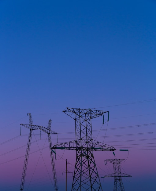 Postes de energia com fios à noite ao pôr do sol