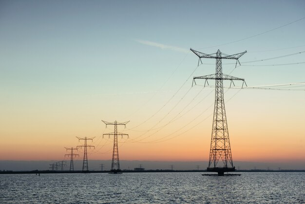 Postes eléctricos en el agua al atardecer