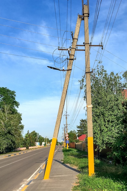 Postes elétricos ao longo da rua vazia da vila e céu azul no dia de verão