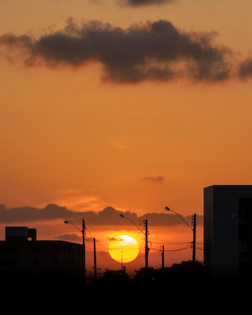 Postes eletrizantes com fundo laranja do céu do sol.