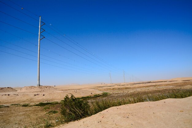 Postes elevados de alta tensão de eletrificação em perspectiva no deserto