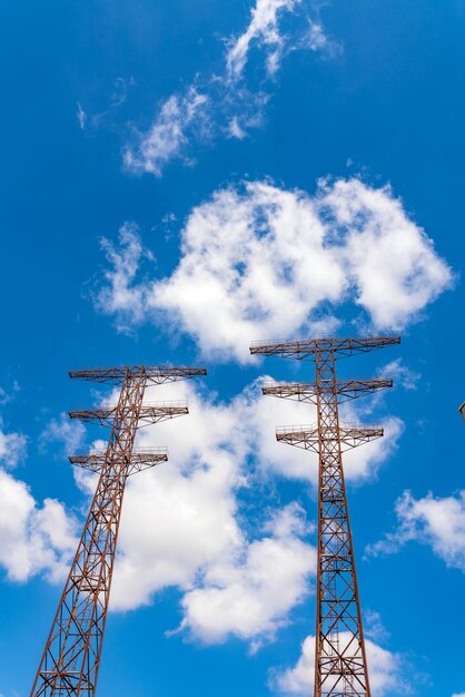 Postes de energía viejos contra el cielo azul