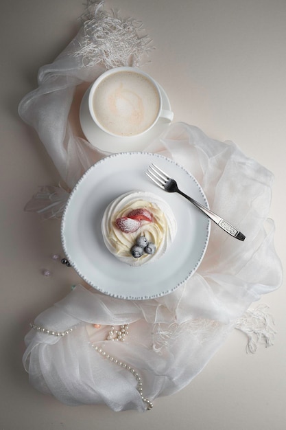 Postre Anna Pavlova con fresa y arándano en un plato blanco con decoración