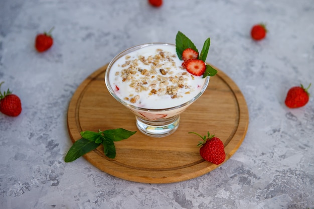 Foto postre de avena con fresas. desayuno saludable de parfait de fresa con frutas frescas, yogur y granola en una mesa gris. de cerca.