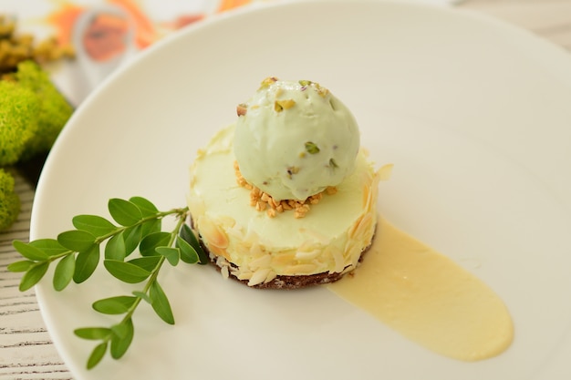 Postre con una bola de helado de pistacho con decoración floral.