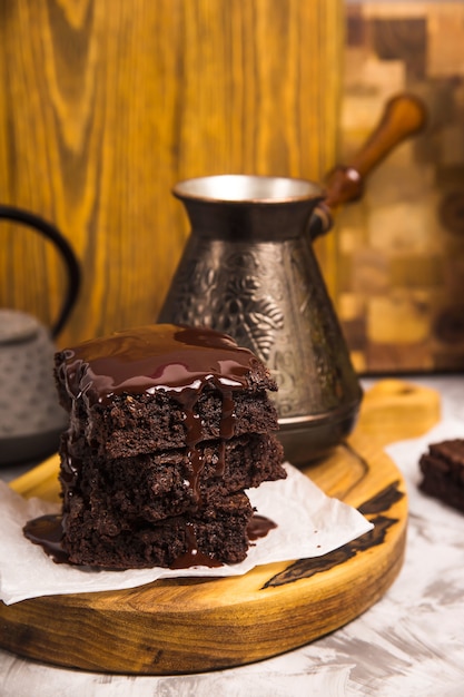 Postre con brownies de cacao en chocolate cerca de tetera y café turco