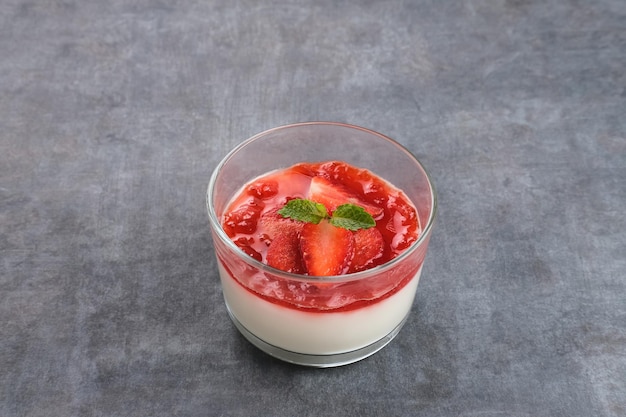 Postre de budín sedoso de vainilla dulce con salsa de fresa fresas frescas en rodajas y hojas de menta