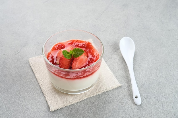 Postre de budín sedoso de vainilla dulce con salsa de fresa fresas frescas en rodajas y hojas de menta