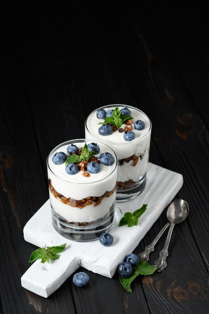 Foto postre casero en capas con queso crema de arándanos frescos o granola de yogur sobre fondo rústico