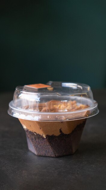 Postre de chocolate con crema y galleta en una taza de plástico