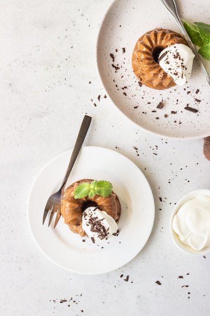 Foto postre de chocolate decorado con crema batida, chocolate rallado y menta. panna cotta.